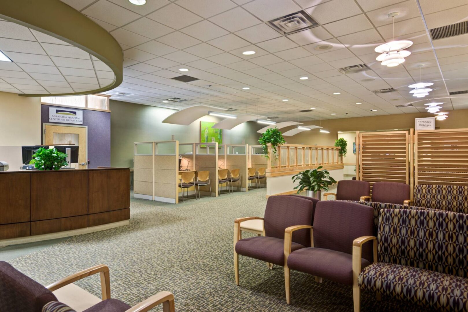 A hospital waiting room with purple chairs and tables.